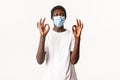 Portrait of satisfied african-american handsome guy in medical mask and beanie, staying protected during covid-19