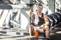 Portrait of satisfied athlete handsome masculine man sitting during treadmill exercise in gym, tired sportsman drinking water in Royalty Free Stock Photo