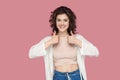 Portrait of satisfied beautiful brunette young woman with curly hairstyle in casual style standing, thumbs up and looking at Royalty Free Stock Photo