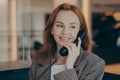 Portrait of satisfied female office worker using black landline phone, calling business partner Royalty Free Stock Photo