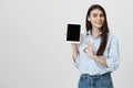 Portrait of satisfied good-looking european customer, showing white tablet to camera and making okay or fine sign with