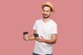 Portrait of satisfied handsome bearded young hipster blogger man in white shirt and casual hat standing with coffee and chatting