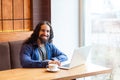 Portrait of satisfied handsome intelligence bearded young adult man freelancer in casual style sitting in cafe and working in Royalty Free Stock Photo