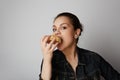 Portrait of a satisfied handsome young woman eating donuts isolated over white background. Royalty Free Stock Photo