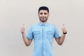 Portrait of satisfied happy handsome young bearded businessman in blue shirt standing, smiling, thumbs up like gesture and looking Royalty Free Stock Photo