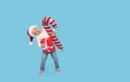 Portrait of a satisfied little child boy in christmas Santa hat. laughing isolated over blue background. Holds a gift box Royalty Free Stock Photo