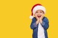 Portrait of a satisfied little child boy in christmas Santa hat. laughing isolated over yellow background. Royalty Free Stock Photo