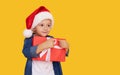 Portrait of a satisfied little child boy in christmas Santa hat. laughing isolated over yellow background. Holds a gift box. Royalty Free Stock Photo