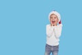 Portrait of a satisfied little child boy dressed in christmas Santa hat. laughing isolated over blue background. Wow face. Royalty Free Stock Photo