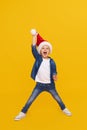 Portrait of a satisfied little child boy dressed in christmas Santa hat. laughing isolated over colored yellow background. Royalty Free Stock Photo