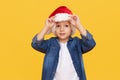 Portrait of a satisfied little child boy dressed in christmas Santa hat. laughing isolated over colored yellow background. Royalty Free Stock Photo