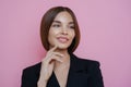 Portrait of satisfied lovely female employee looks away with dreamy cheerful expression, has manicure, dressed in black outfit,