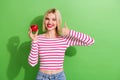 Portrait of satisfied lovely nice girl dressed striped clothes hold apple showing thumb up approve isolated on green Royalty Free Stock Photo