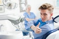 Portrait of satisfied man visiting dentist giving thumbs up in the dental clinic Royalty Free Stock Photo