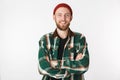 Portrait of satisfied man wearing hat and plaid shirt smiling with arms crossed, while standing isolated over white background Royalty Free Stock Photo