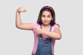 Portrait of satisfied strong brunette young girl in casua pink t-shirt and blue overalls standing looking at camera and pointing