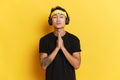 Portrait of satisfied and thankfull ethnic young man with tattoo listens music via wireless headphones enjoys his Royalty Free Stock Photo