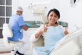 Portrait of satisfied woman visiting dentist giving thumbs up in dental clinic Royalty Free Stock Photo