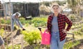 Portrait of an satisfied woman with watering can for watering plants in garden Royalty Free Stock Photo