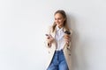 Portrait of a satisfied young businesswoman using mobile phone while holding cup of coffee to go over white background Royalty Free Stock Photo
