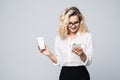 Portrait of a satisfied young business woman using mobile phone while holding cup of coffee to go over white background Royalty Free Stock Photo