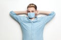 Portrait of satissfied and successful handsome young man with surgical medical mask in blue shirt standing, raised arms holding Royalty Free Stock Photo