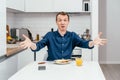 Portrait of scandalized, indignant middle-aged man with short ginger hair in blue shirt rebelling with arms raised.