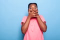 Portrait of scared african american young woman covering mouth looking into camera Royalty Free Stock Photo