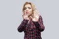 Portrait of scared beautiful blonde young woman in casual red checkered shirt standing with blocking hands and panic Royalty Free Stock Photo