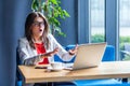 Portrait of scared beautiful stylish brunette young woman in glasses sitting, looking and reading some news at her laptop screen