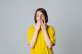 Portrait of a scared teen girl in yellow casual t shirt, looking away with wide opened eyes, covering mouth her hands, stand over Royalty Free Stock Photo