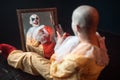 Bloody clown with crazy eyes sitting at the mirror Royalty Free Stock Photo