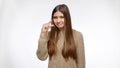 Portrait of sceptic girl showing small size with hand over white studio background