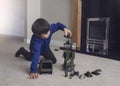 Portrait of School boy lying down on the carpet floor playing with soldiers, military car and figurine toys, Happy Kid playing