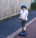 Portrait school boy ride a scooter to school, Child wearing safety helmet riding a roller, Kid playing with his toy outside, Activ Royalty Free Stock Photo