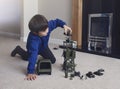 Portrait of School boy sitting on carpet floor playing with soldiers, military car and figurine toys, Happy Kid playing wars and