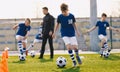 Portrait of school boys training soccer with young coach on football field