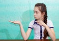 Portrait of a school girl with a serious face, who points with her hands at a copy of the text space Royalty Free Stock Photo