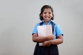 A school girl wearing uniform holds note books in hand Royalty Free Stock Photo