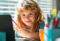 Portrait of school kid boy siting on table doing homework. Child holding pencil and writing. Boy drawing on white paper Royalty Free Stock Photo