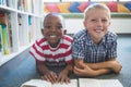 Portrait of school kids reading book in library Royalty Free Stock Photo