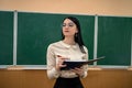 portrait of school teacher wear white blouse and glasses near on the background of the blackboard Royalty Free Stock Photo