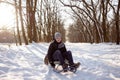 portrait of a schoolboy boy playing outdoors with snow. Happy child sits on a sled on a winter day in a park or forest Royalty Free Stock Photo