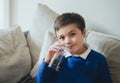 Portrait schoolboy drinking soda or soft drink with glass,Child enjoying cold fizzy dink while watching TV after back from school,