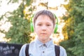 Portrait of a schoolboy in headphones with a backpack over his shoulders.