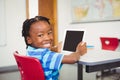 Portrait of schoolboy holding digital tablet in classroom