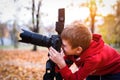 Portrait of schoolboy takes pictures on a SLR camera. Autumn Park