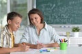 Portrait of schoolboy and teacher sitting at classroom Royalty Free Stock Photo