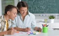 Portrait of schoolboy and teacher sitting at classroom Royalty Free Stock Photo