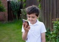 Portrait schoolboy using smartphone typing text messages,Happy kid standing outdoor using cellphone chatting with friends,Child